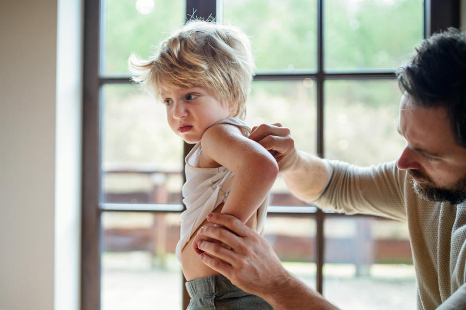 A man examines a young child’s lower back.