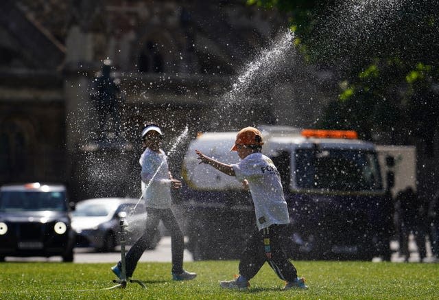 Children run through a sprinkler on Parliament Square in London as the heatwave continues in the UK