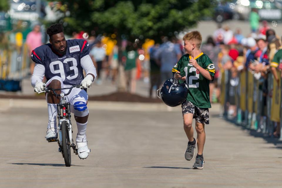 Houston Texans defensive end Joel Heath rides a fan's bike to a joint NFL football practice with the Green Bay Packers  in Green Bay, Wis. 