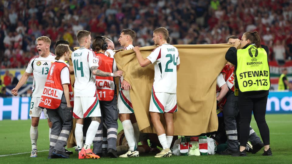 Hungary players hold up blankets as they assist medical staff by covering up Varga as he receives medical attention. - Carl Recine/Getty Images