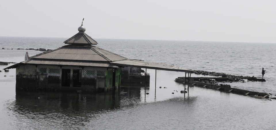 A man fishes near an abandoned mosque in Jakarta, Indonesia, Saturday, July 27, 2019. Indonesia's President Joko Widodo said in an interview that he wants to see the speedy construction of the giant sea wall to save the low-lying capital of Jakarta from sinking under the sea, giving renewed backing to a long-delayed multi-billion-dollar mega project. (AP Photo/Achmad Ibrahim)