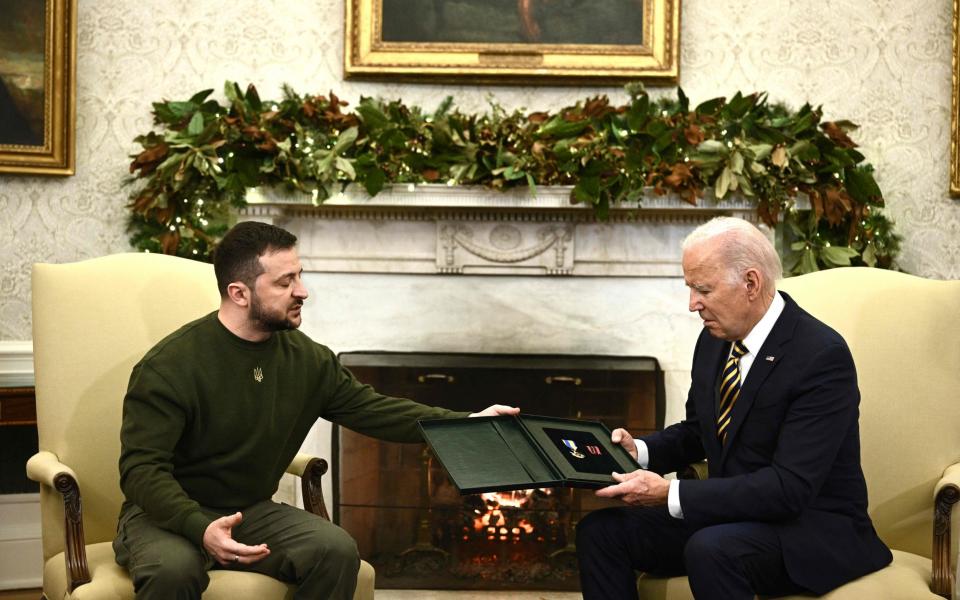 Volodymyr Zelensky presents Joe Biden with a bravery medal. - AFP