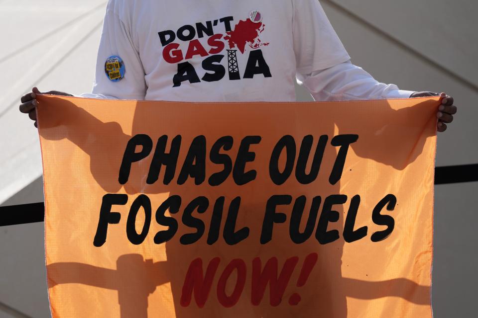 A person holds a sign reading "phase out fossil fuels now!" during a demonstration for a just and equitable transition from fossil fuels at the COP28 U.N. Climate Summit, Tuesday, Dec. 5, 2023, in Dubai, United Arab Emirates.