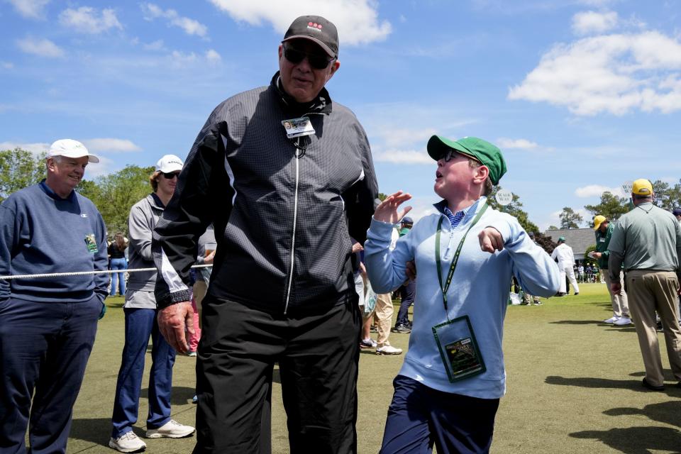 A guard escorts a young patron to the front of the row to watch as golfers make their way to the first tee on Sunday.