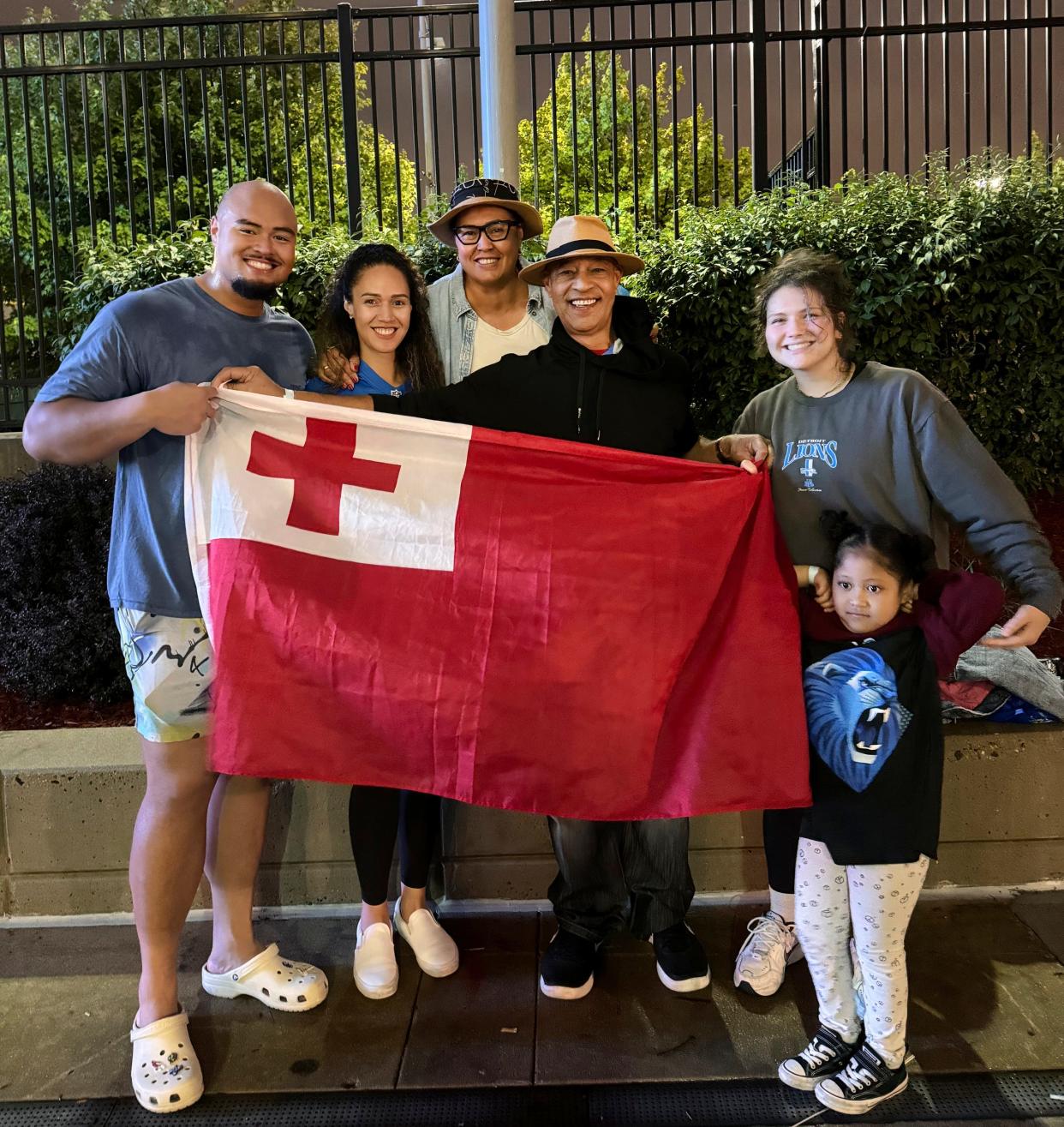 Lions offensive tackle Giovanni Manu, left, poses with the flag of Tonga with his family sister Madelene Manu, mother Alvina Manu, father John Manu, his girlfriend Kendra Lee Roberts, and niece Rosie Manu on Thursday, Aug. 8, 2024 after he played his first NFL preseason game against the New York Giants.