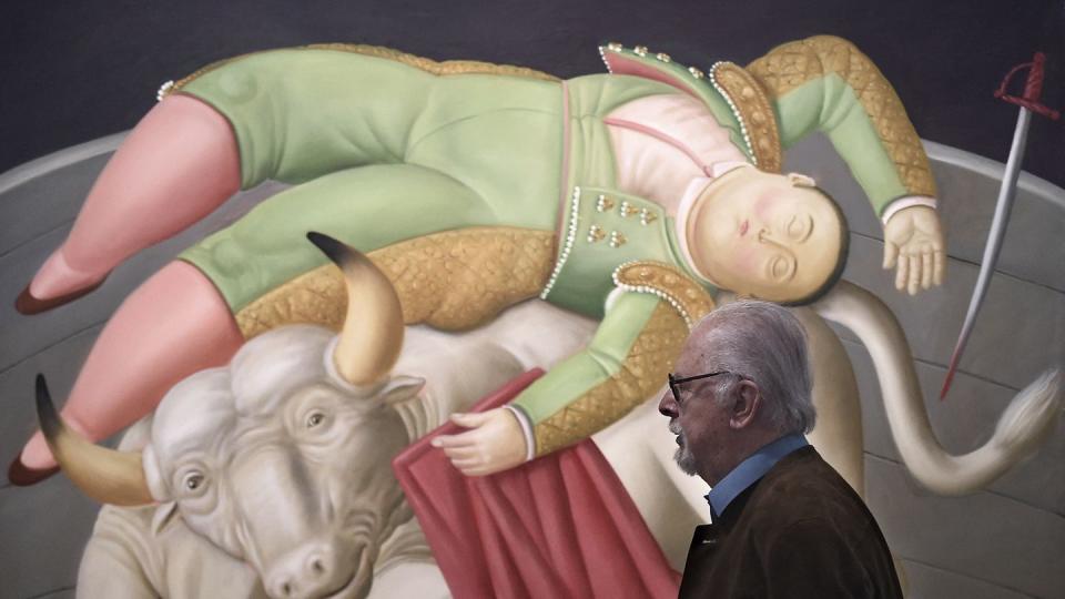 fernando botero standing in front of a painting depicting a bull and matador