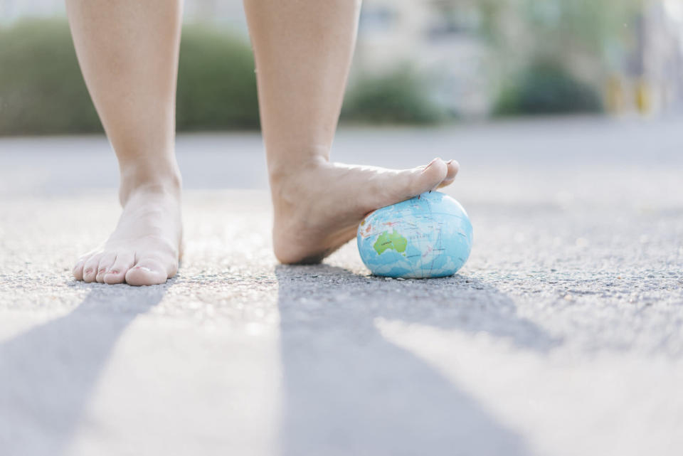 Foot of young woman stepping on globe. Source: Getty Images