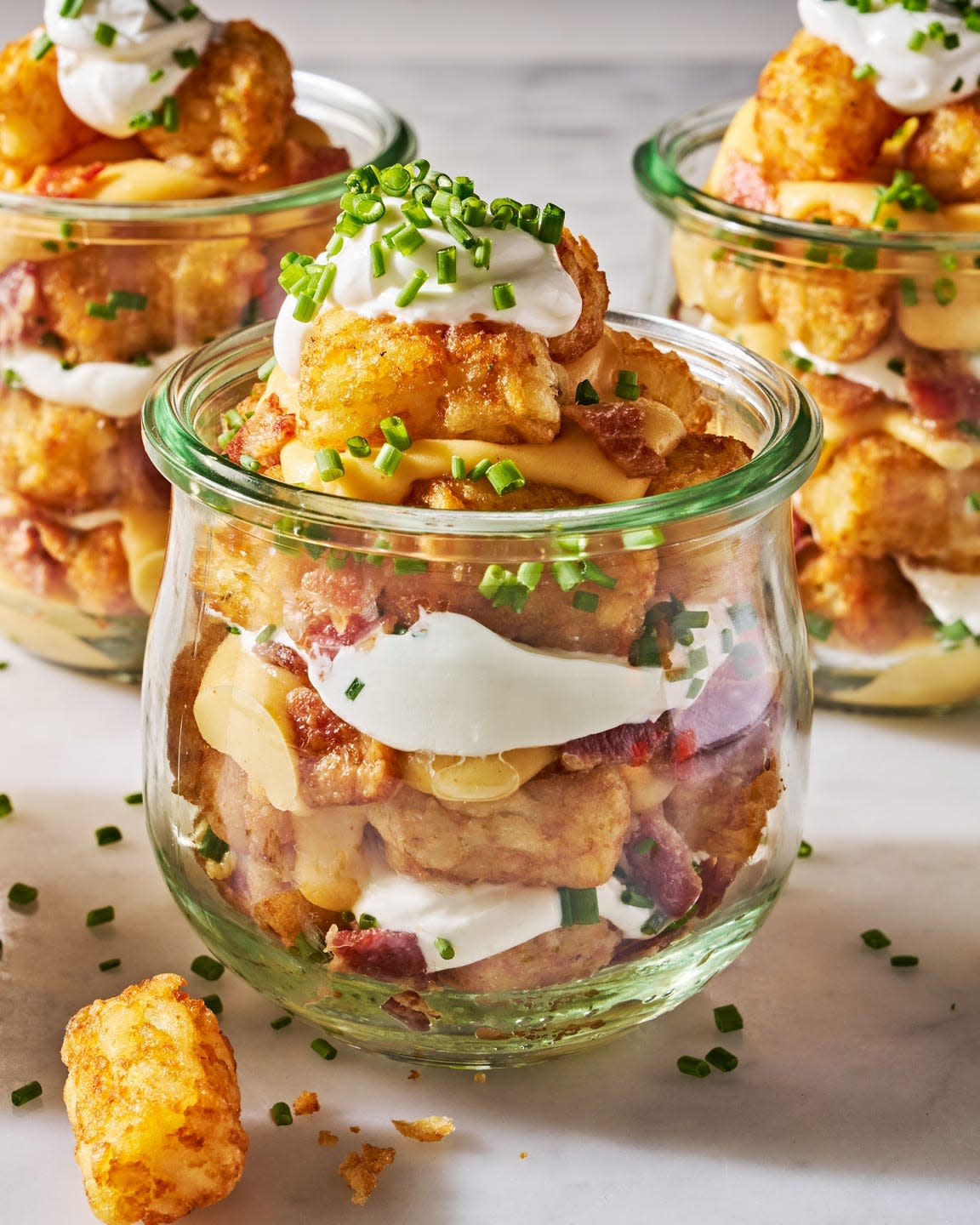 tater tots in a mason jar layered with sour cream, cheese, bacon, and chives