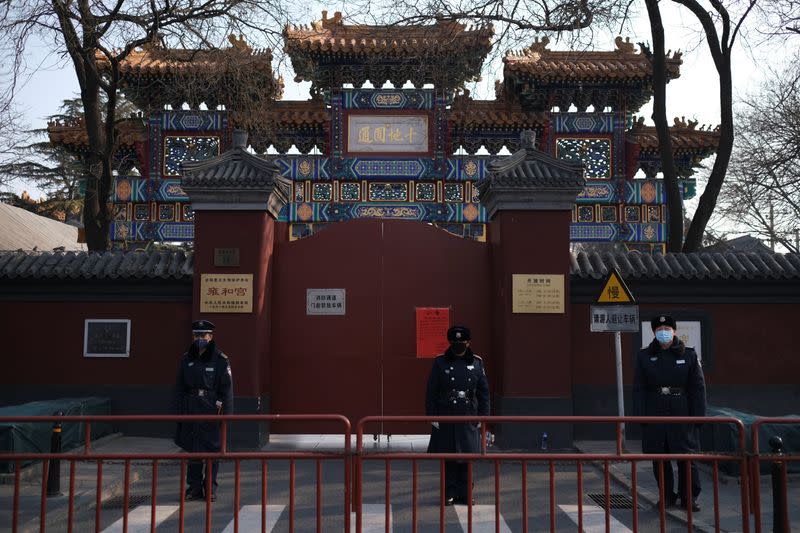 Police officers stand guard in front of the closed gate of Lama Temple where a notice saying that the temple is closed for the safety concern following the outbreak of a new coronavirus is seen, in Beijing