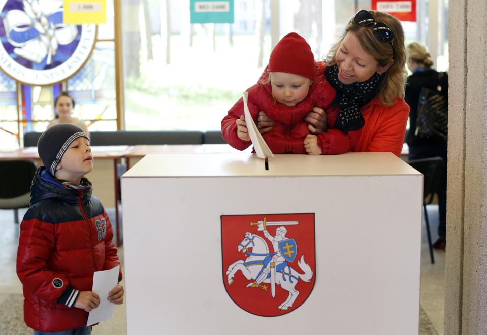 A woman with a child casts her ballot at a polling station during the first round of voting in presidential elections in Vilnius, Lithuania, Sunday May 11, 2014. (AP Photo/Mindaugas Kulbis)