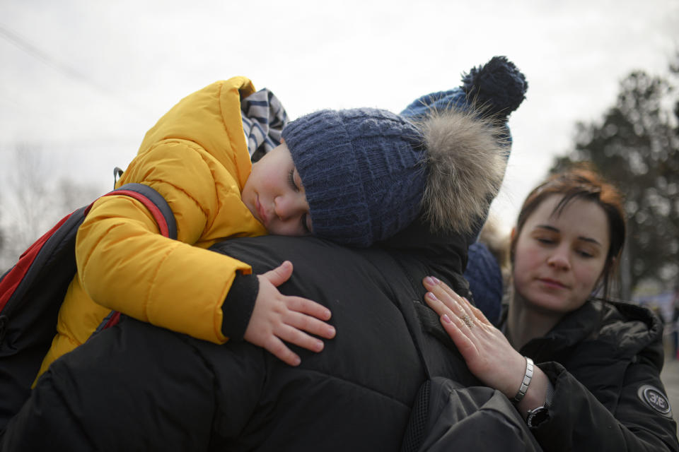 A man hugs his twin boys after they fled the conflict from neighbouring Ukraine at the Romanian-Ukrainian border, in Siret, Romania, Sunday, Feb. 27, 2022. Since Russia launched its offensive on Ukraine, more than 200,000 people have been forced to flee the country to bordering nations like Romania, Poland, Hungary, Moldova, and the Czech Republic — in what the U.N. refugee agency, UNHCR, said will have "devastating humanitarian consequences" on civilians. (AP Photo/Andreea Alexandru)