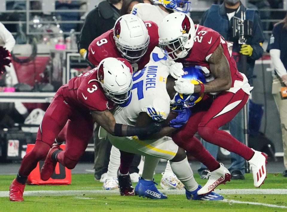 Arizona Cardinals safety Budda Baker (3), linebacker Isaiah Simmons (9), and cornerback Robert Alford (23) tackle Los Angeles Rams running back Sony Michel (25) at State Farm Stadium in Glendale, Ariz.