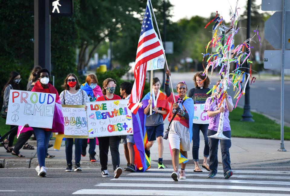 People hold signs as they cross Minnesota Highway 23 during the Community Pride and Peace Walk Tuesday, Sept. 14, 2021, in St. Cloud.