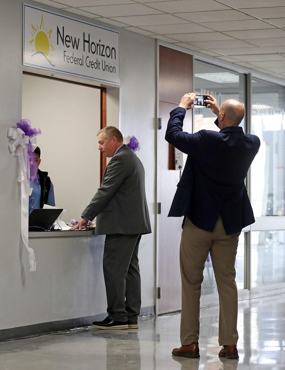 Barberton Principal Henry Muren, center, is photographed by Roger Wright, director of the Four Cities Compact, as he opens a savings account at New Horizon Federal Credit Union inside Barberton High School.