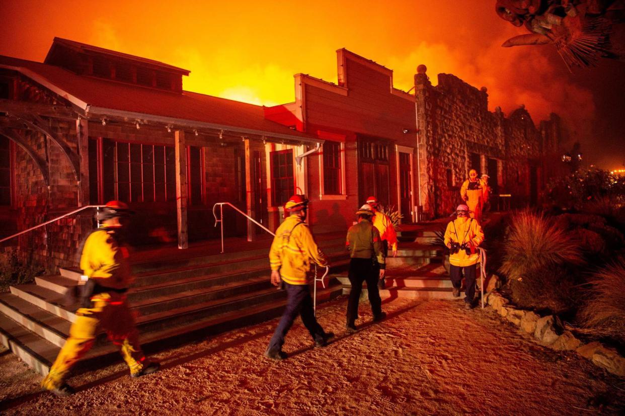 Firefighters survey the Soda Rock Winery as it burns during the Kincade fire as flames race through Healdsburg, Calif. on Oct. 27, 2019. Powerful winds were fanning wildfires in northern California in "potentially historic fire" conditions, authorities said October 27, as tens of thousands of people were ordered to evacuate and sweeping power cuts began in the U.S. state.