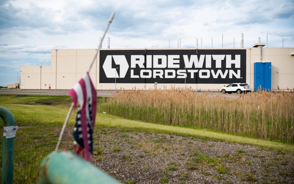 An American flag hangs at half mast in front of the Lordstown Motors factory in Ohio, a giant boxy beige building hung with a huge banner that reads "RIDES WITH LORDSTWN" - Dustin Franz/Bloomberg