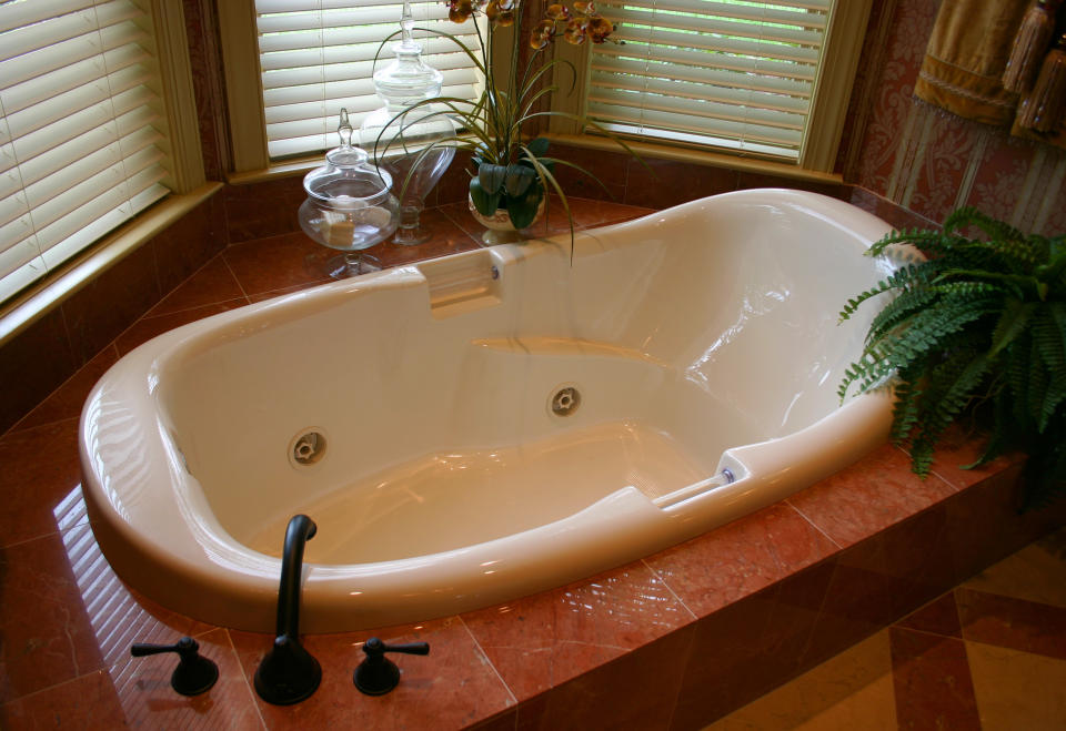 jetted tub surrounded by reddish brown tiles