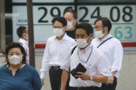 People walk by an electronic stock board of a securities firm in Tokyo, Wednesday, Sept. 22, 2021. Asian shares were mostly lower on Wednesday after major indexes ended mixed on Wall Street.(AP Photo/Koji Sasahara)