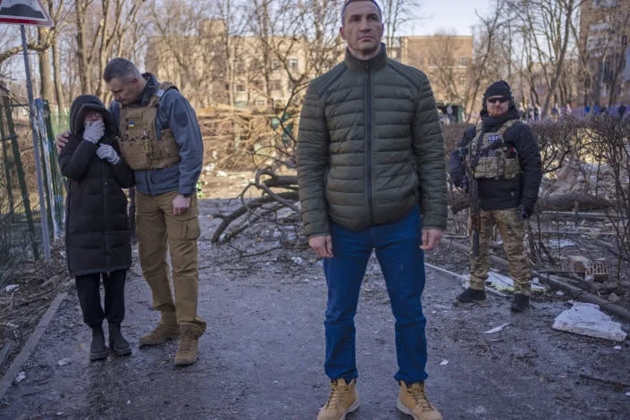 El alcalde de Kiev, Vitali Klichkó, a la izquierda, consolando a una mujer en el sitio donde un bombardeo dañó edificios residenciales en Kiev, Ucrania, el viernes. (Rodrigo Abd/AP)
