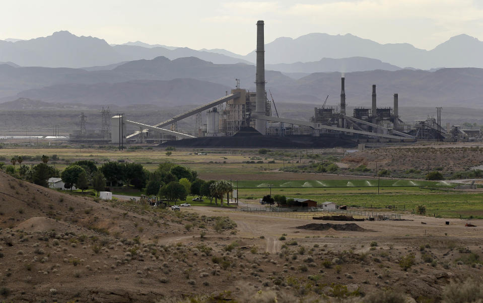 In this Monday, May 14, 2012, photo, the Reid-Gardner power station is seen near a farm on the Moapa Indian Reservation, in Moapa, Nev. Across the country, a disproportionate number of power plants operate near Indian tribal lands. Some tribes embrace the plants, which provide jobs and tax dollars to their communities. But a small group have begun to protest the plants in recent years, asking that they be closed down. (AP Photo/Julie Jacobson)