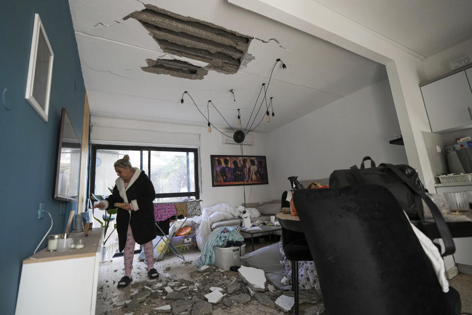 An Israeli woman inspects damage to her house hit by a rocket fired from the Gaza Strip, in Sderot, southern Israel, Friday, April 7, 2023. Israel conducted rare airstrikes in Lebanon on Friday, a sharp escalation that sparked fears of a broader conflict after militants fired dozens of rockets from Lebanon into Israeli territory. Israel also continued bombarding the Gaza Strip as Palestinian militants responded with more rockets. (AP Photo/Tsafrir Abayov)