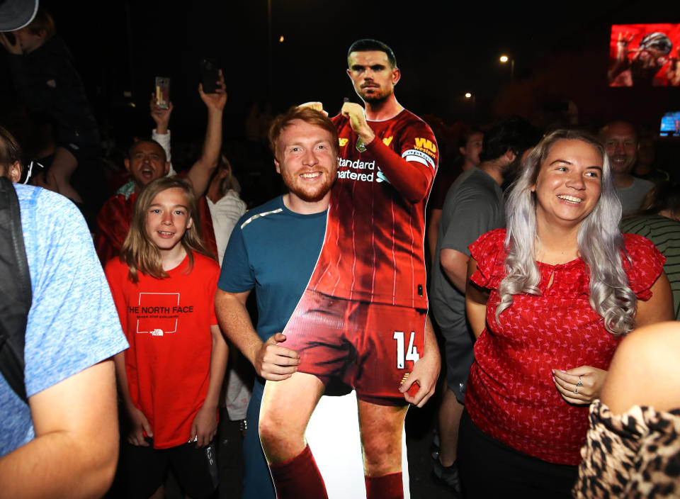 A Liverpool fan holds a cutout of captain Jordan Henderson outside Anfield.