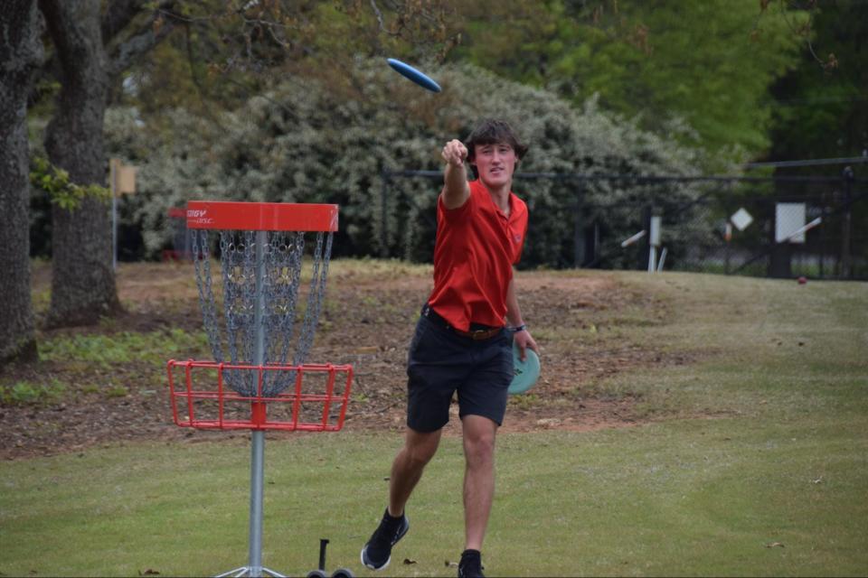 Maxwell Ford throws a disc to the disc golf basket at the entrance to the UGA Golf Course on April 11. Ford played disc golf with teammates Buck Brumlow and Blake Parkman after taking their team photo.