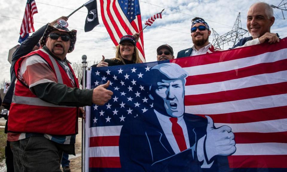 Trump supporters hoist a flag and give the thumbs-up.