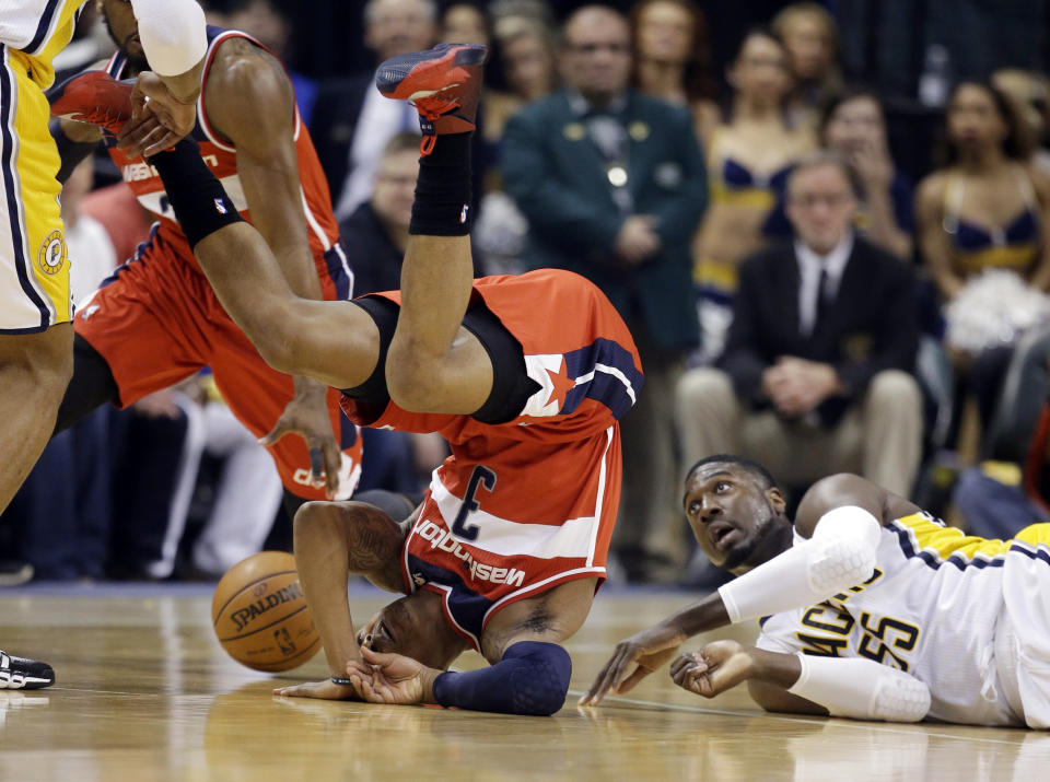 El escolta Bradley Beal de los Wizards de Washington cae frente al centro Roy Hibbert de los Pacers de Indiana en los playoffs de la NBA el miércoles 7 de mayo de 2014. (AP Foto/Darron Cummings)