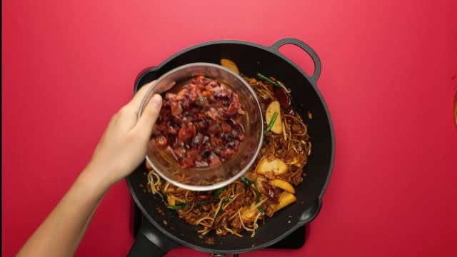 Adding cockles to char kway teow in pan