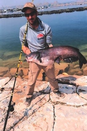 Coy Bowyer holds up his record-setting catfish caught in the Pueblo Reservoir in 2023.