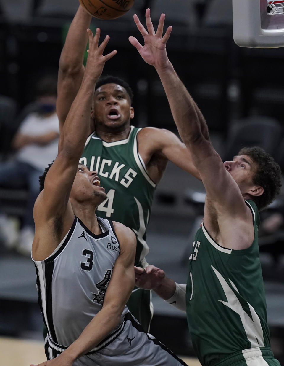 San Antonio Spurs forward Keldon Johnson (3) shoots against Milwaukee Bucks forward Giannis Antetokounmpo, center, and Milwaukee Bucks center Brook Lopez, right, during the second half of an NBA basketball game in San Antonio, Monday, May 10, 2021. (AP Photo/Eric Gay)