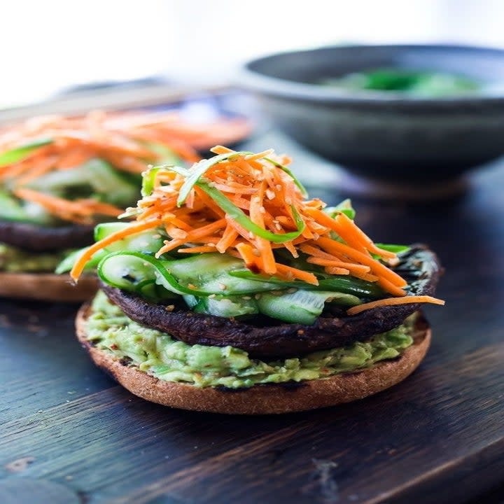 An open face mushroom burger with cucumber and carrots.