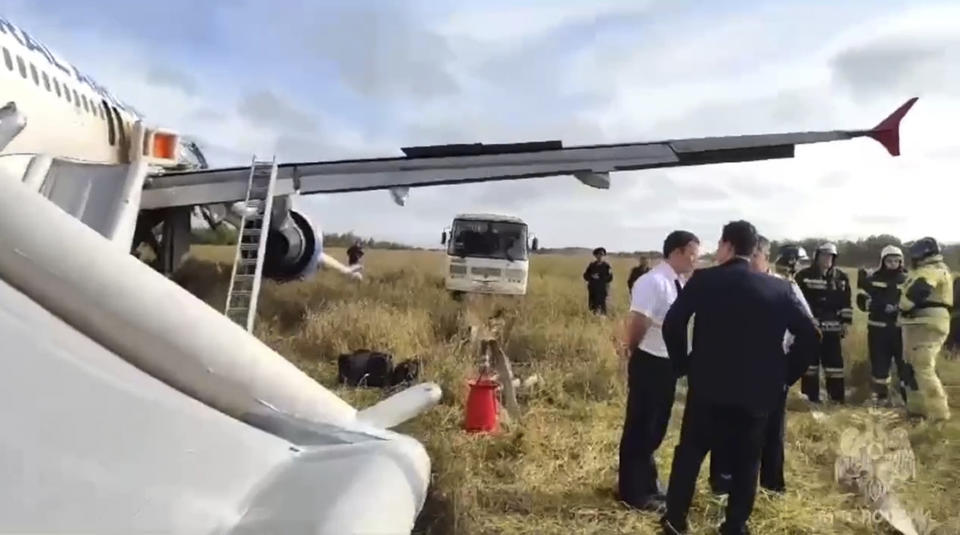 In this image made from video provided by Russian Emergency Situations Ministry press service, rescue workers an investigators stand next to an Airbus A320 of Ural Airlines after emergency landing near Ubinskoye village, Novosibirsk Region, Russia, Tuesday, Sept. 12, 2023. An Airbus A320 with 161 passengers onboard has performed an emergency landing in a field in the Novosibirsk Region, according to Ural Airlines, TASS reported. (Ministry of Emergency Situations press service via AP)