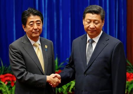 FILE PHOTO: China's President Xi Jinping (R) shakes hands with Japan's Prime Minister Shinzo Abe during their meeting at the Great Hall of the People, on the sidelines of the Asia Pacific Economic Cooperation (APEC) meetings, in Beijing November 10, 2014. REUTERS/Kim Kyung-Hoon/File Photo