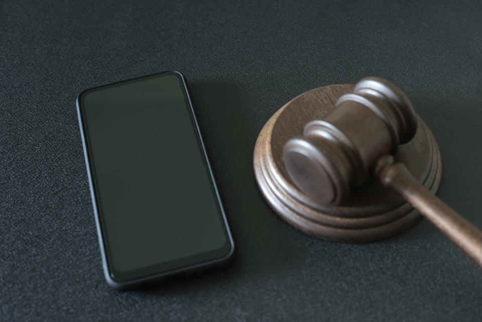 Smartphone and judges gavel on black background