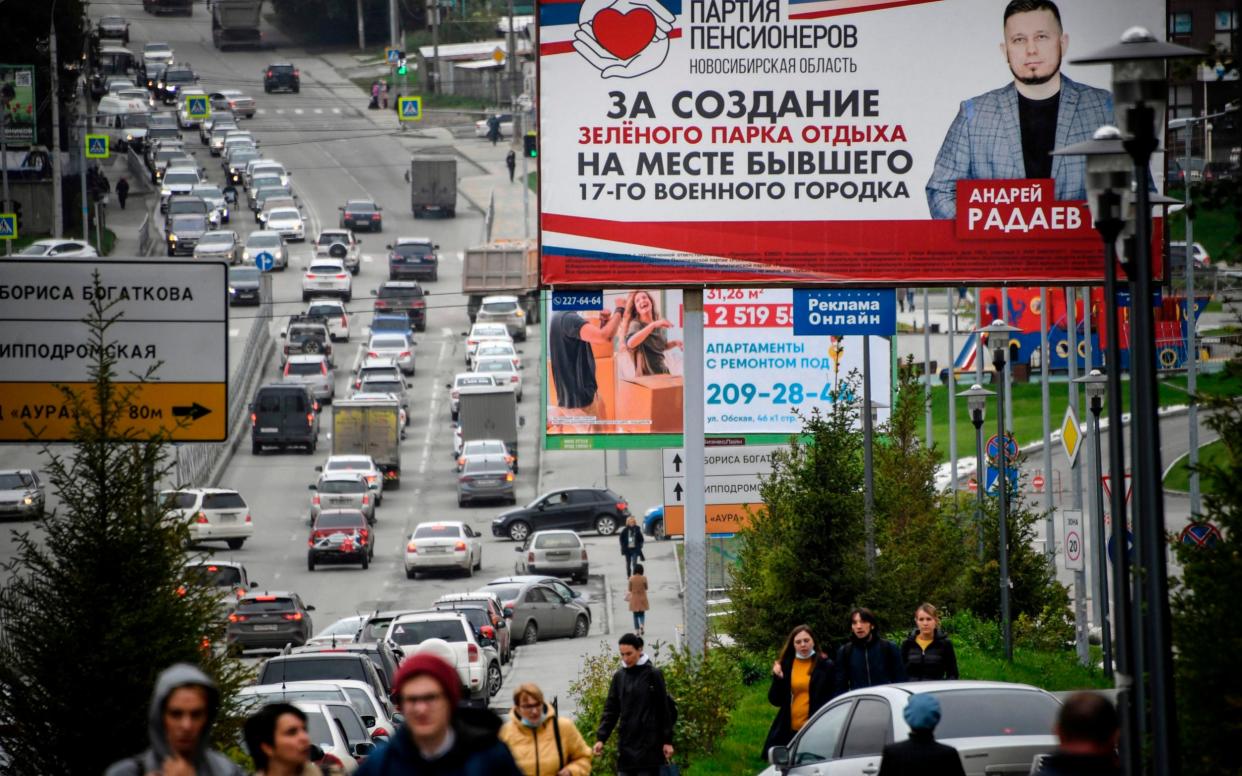 People walk in front of a Pensioners of Russia party campaign billboard for September 13 regional elections in Novosibirsk on September 9, 2020.  - ALEXANDER NEMENOV/AFP via Getty Images