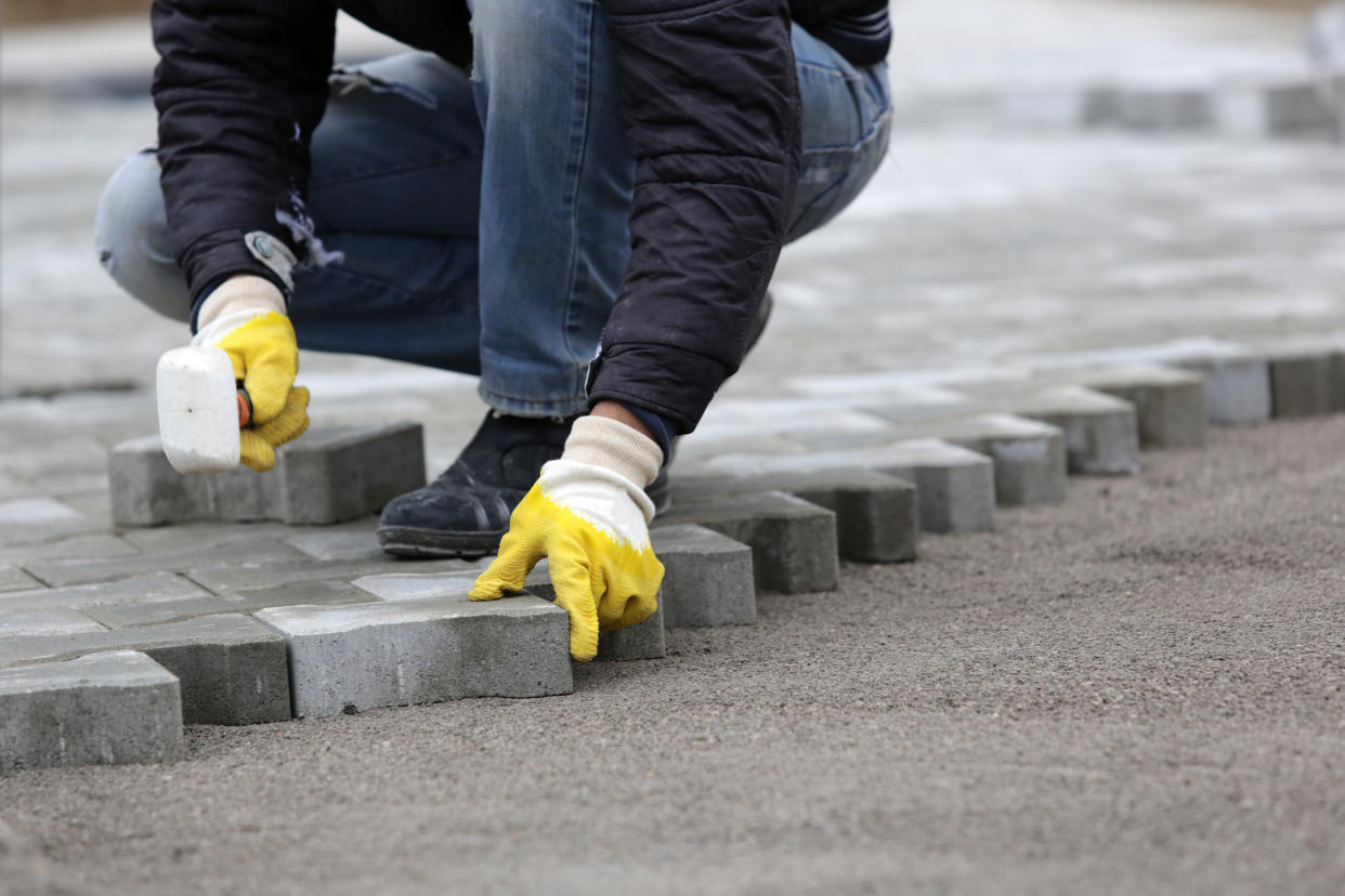 Paving stone worker is putting down pavers during a construction of a city street.