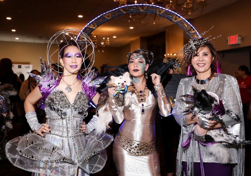 Women stand for a portrait holding dogs at the 17th annual New York Pet Fashion Show