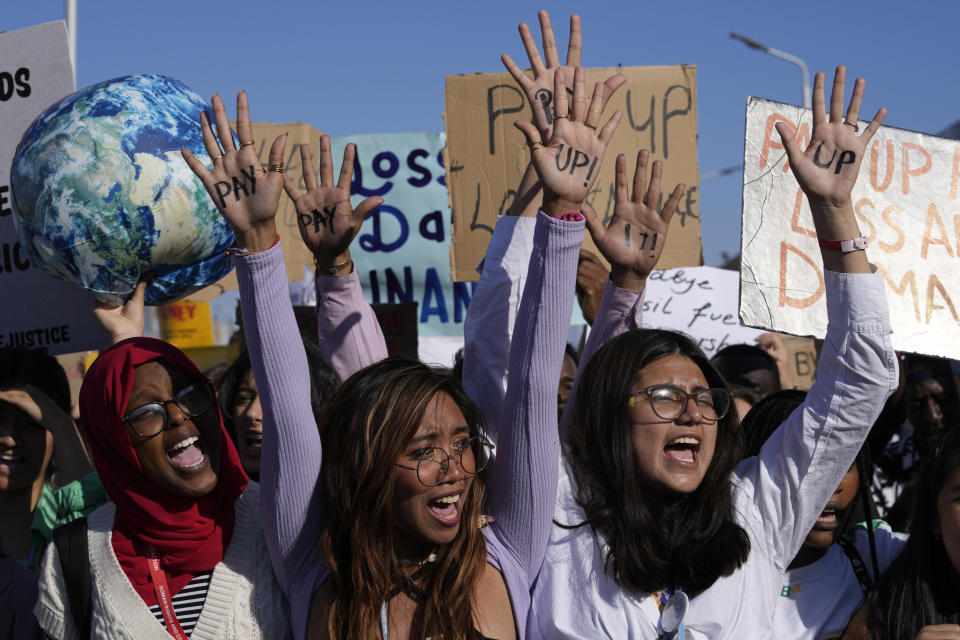 Climate activist Mitzi Jonelle Tan, center, of the Philippines, hands say "pay up" as she and others take part in a protest at the COP27 U.N. Climate Summit, Friday, Nov. 18, 2022, in Sharm el-Sheikh, Egypt. (AP Photo/Peter Dejong)