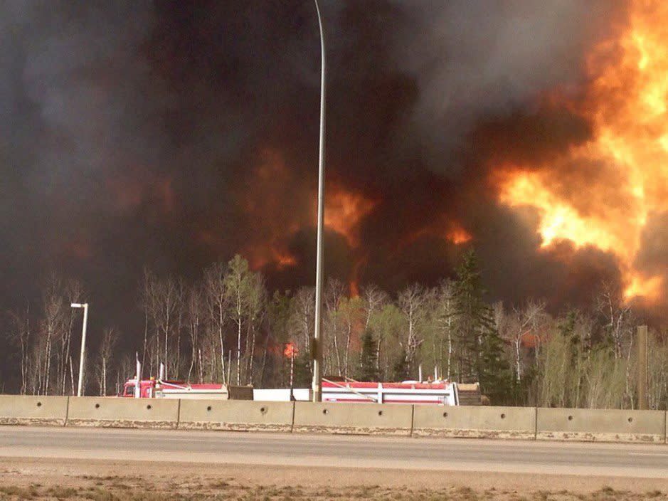 Trees burn near a road in Fort McMurray, Alberta on Tuesday May 3, 2016 in this image provide by radio station CAOS91.1 / THE CANADIAN PRESS/HO-CAOS91.1 (KAOS)