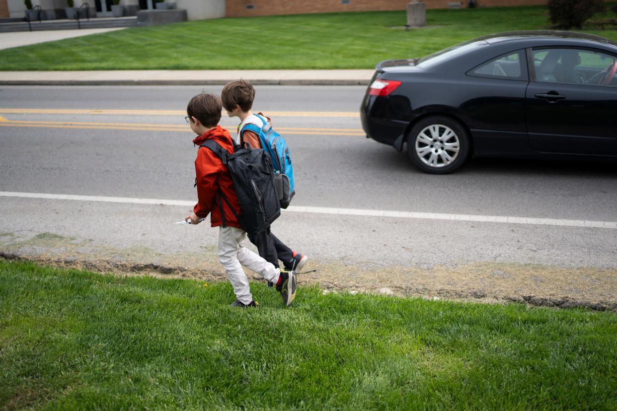 Henry Meyer, 10, and Elliot Meyer, 7, walk home from school though neighbors' yards along Cooke Road in Columbus' Clintonville neighborhood, where there are no sidewalks along the road. Their parents, Chuck Meyer and Linda Baird, worry about their kids walking home along the busy street after school and wish sidewalks would be installed through their neighborhood.