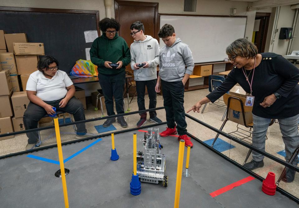 Southwest Detroit's Clippert Multicultural Magnet Honors Academy robotics students Tiziano Garcia, 13, left, Marcus Barber, 14, Andres Garay, 13, Angel Garcia, 11, look on as their science teacher, Tracy Ortiz, works with the team with their robot as they prepare for an upcoming competition Tuesday, Nov. 22, 2022.