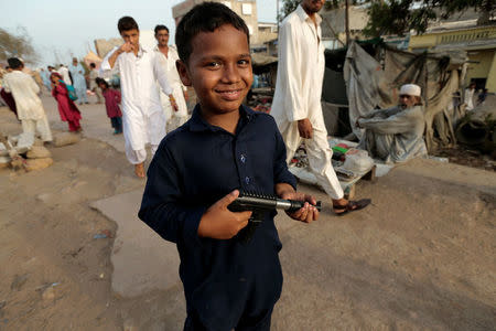 A boy poses for a picture with his toy gun at a market held along the platform of the disused Lyari station in Karachi, Pakistan, May 24, 2017. REUTERS/Caren Firouz