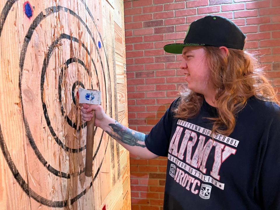 Source Code Escape Games assistant manager Nathanael Colbenson pries out an axe he threw at a wood board in The Broad Axe Throwing Room.