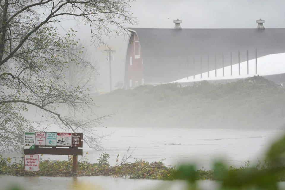 Recreation signs and a barn are shown near rising water from the Snoqualmie River, Friday, Nov. 12, 2021, as rain falls near Fall City, Wash. Forecasters said the storms are being caused by an atmospheric river, known as the Pineapple Express and rain was expected to remain heavy in Oregon and Washington through Friday night. (AP Photo/Ted S. Warren)