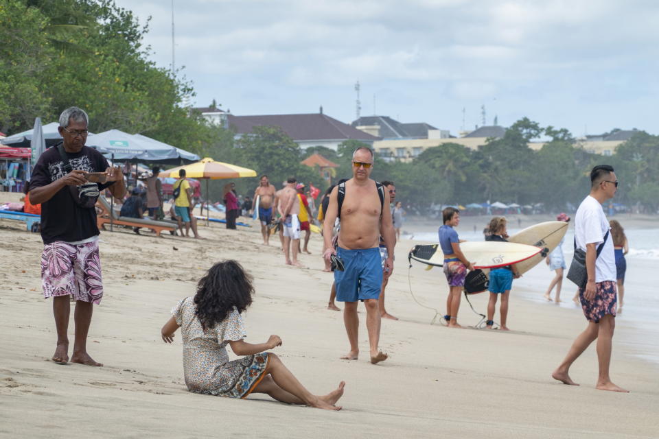 Tourists walk at a beach in Kuta, Bali. Source: EPA via AAP