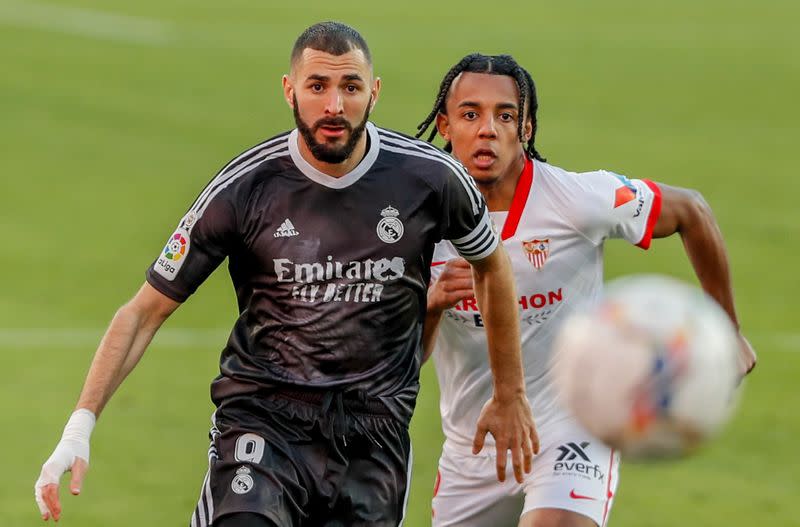 El delantero francés del Real Madrid Karim Benzema disputa un balón con su compatriota Jules Koundé del Sevilla en el partido de La Liga disputado en el Estadio Ramón Sánchez-Pizjuán de Sevilla, España.