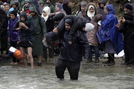 Refugees and migrants cross a river near the Greek-Macedonian border to return to Greece, after an unsuccessful attempt to enter Macedonia, west of the village of Idomeni, Greece, March 15, 2016. REUTERS/Alexandros Avramidis