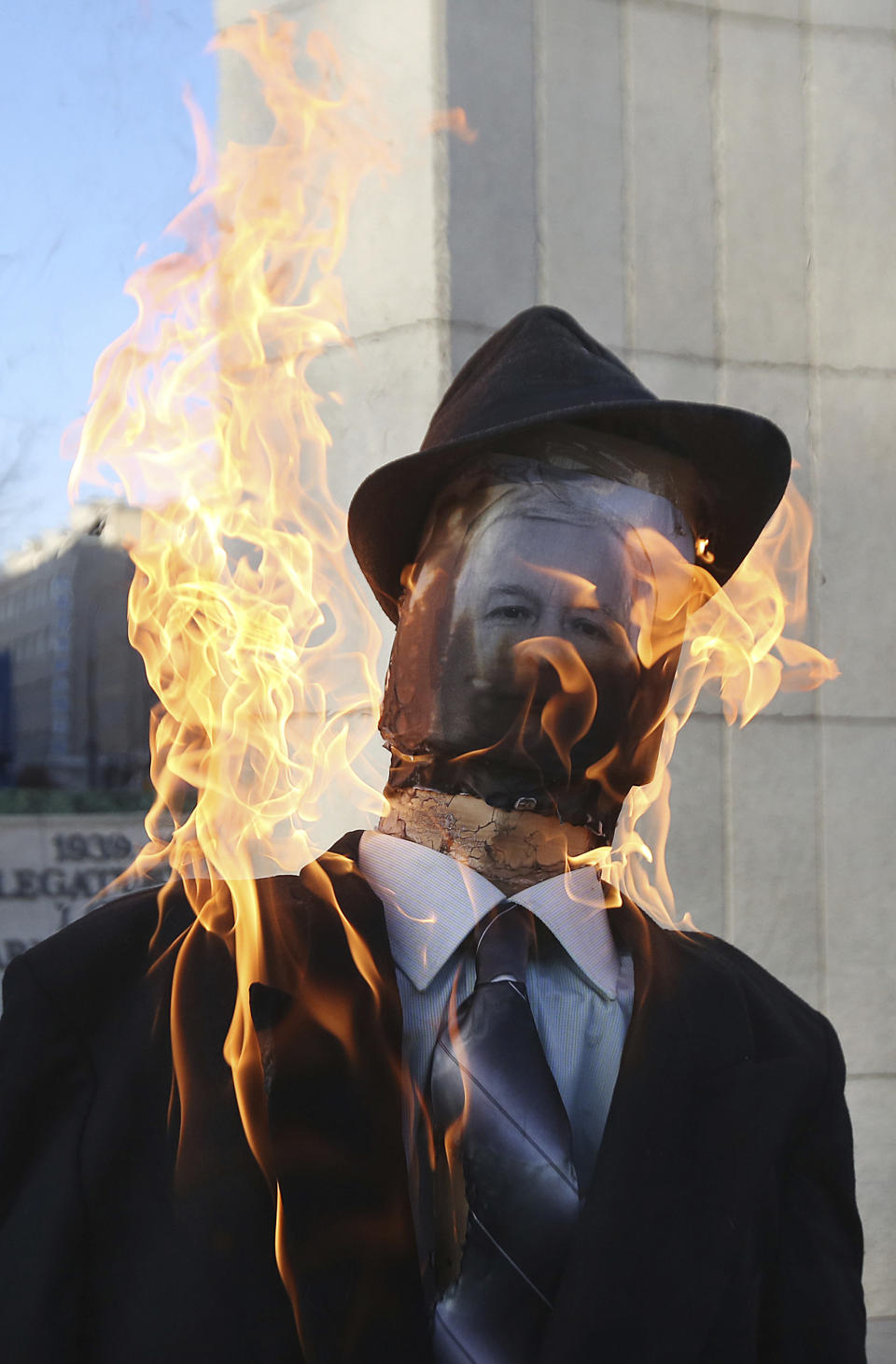 An effigy of Jaroslaw Kaczynski, the powerful head of Poland's ruling conservative Law and Justice party is burning before the parliament building in Warsaw, Poland, Tuesday, Dec. 13, 2016, the 35th anniversary of the imposition of martial law clampdown. A government opponent protests the ruling party's policy saying it does not protect families in trouble. (AP Photo/Czarek Sokolowski)